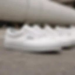 A close-up of all white Vans athletic shoes on a skateboard